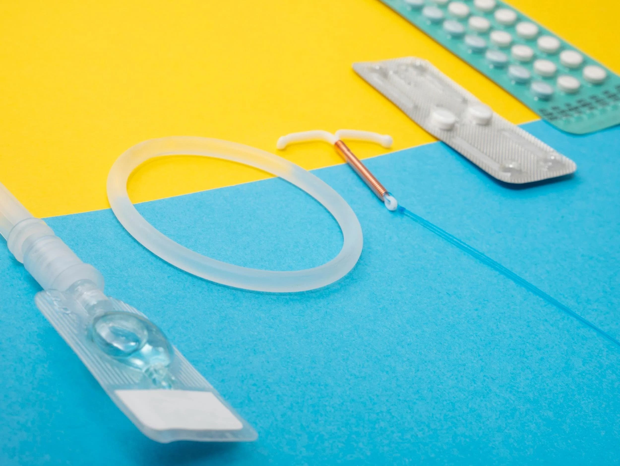 Contraceptive and reproductive health supplies arranged on a blue and yellow surface